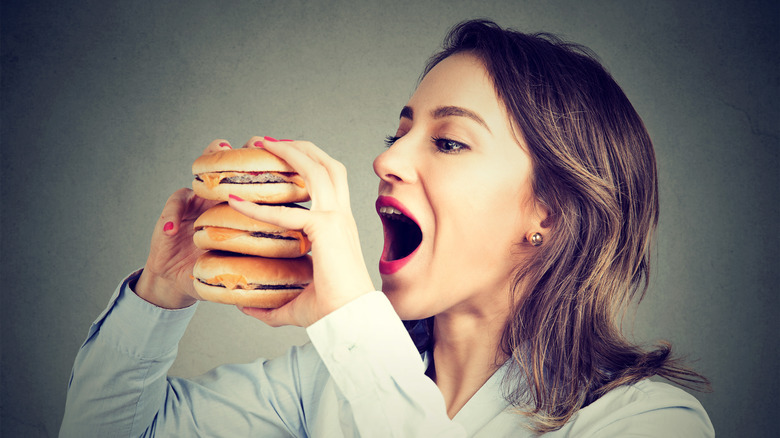 Woman eating craving a tasty double burger.