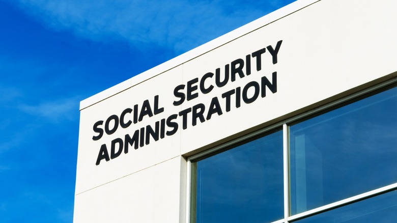 Black "Social Security Administration" lettering above reflective windows on a white building under a blue sky