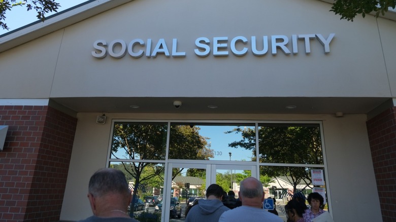 People gathered outside the glass entrance of a Social Security office, with large lettering above the doors