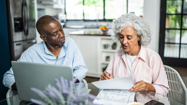 Mature couple sitting at table looking at paperwork.