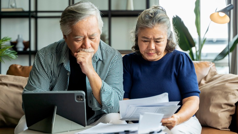 Senior couple checking finances together on sofa