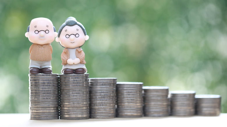senior figurines standing on stacks of coins
