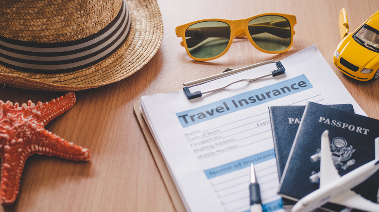 A travel insurance form next to travel related items