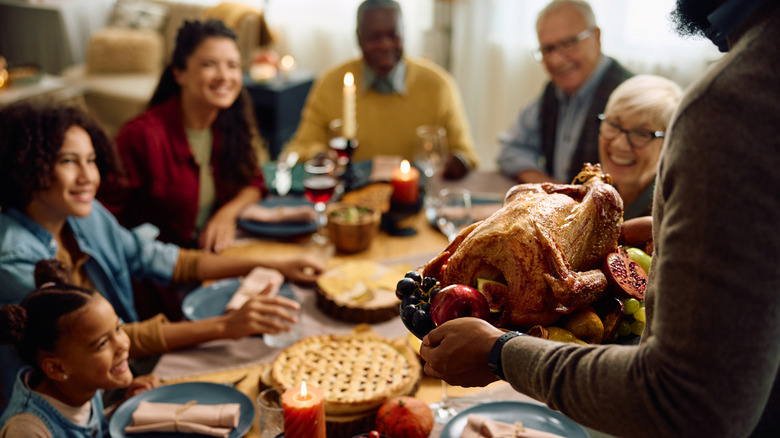 smiling family awaits turkey dinner at table