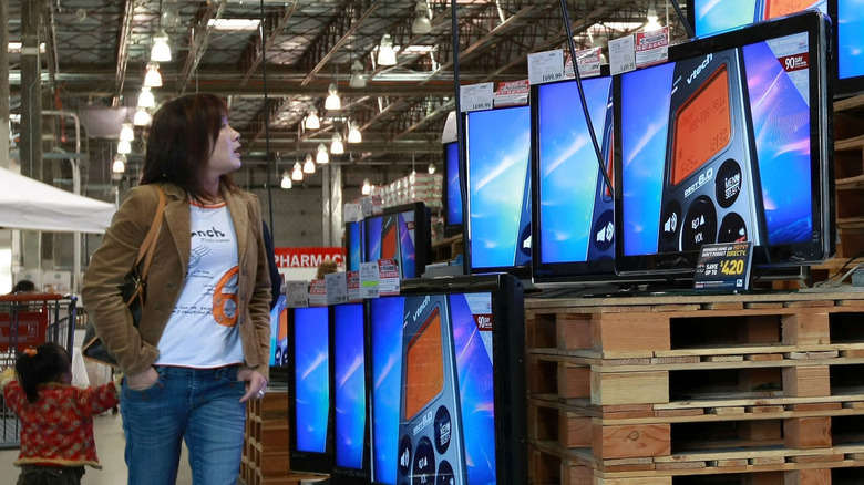 A young woman and a small child looking at TVs in a Costco