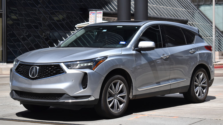 A silver Acura RDX SUV vehicle on a city street.
