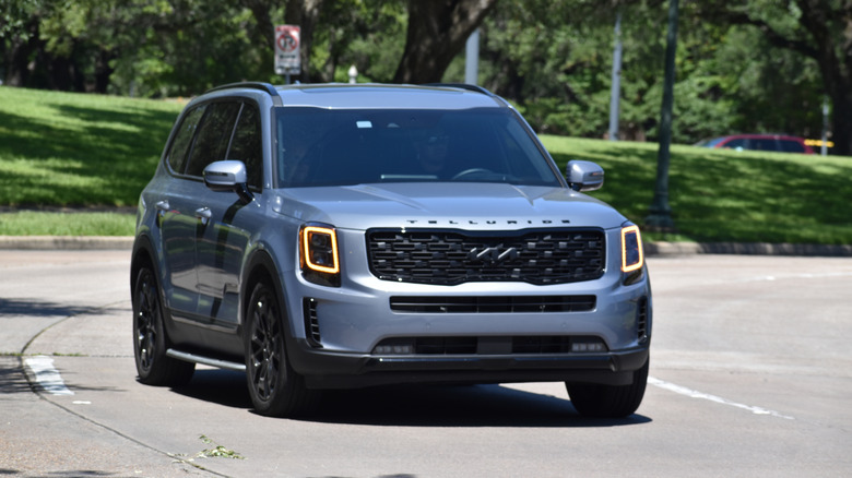A blue Kia Telluride driving on the street.