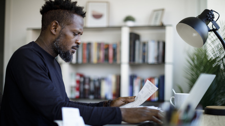 man looking at his paycheck and bills