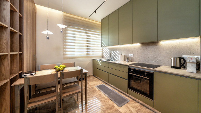 Flat front olive green kitchen cabinets in a kitchen.