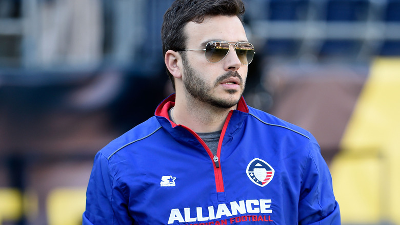 Charlie Ebersol in an Alliance of American Football jacket and aviators on a football field