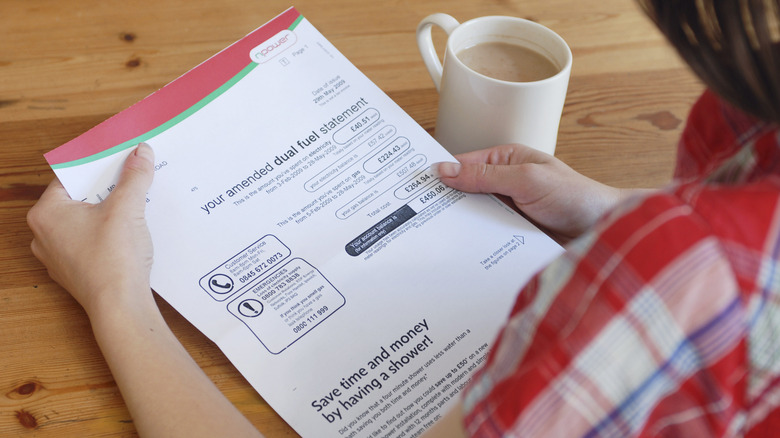 Woman with cup of coffee looking at utility bill