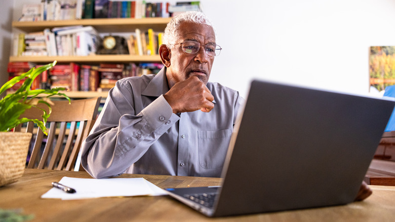 man with white hair looking at laptop computer