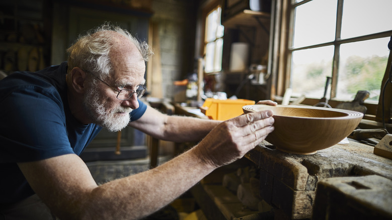 man with grey hair working on wooden bowl