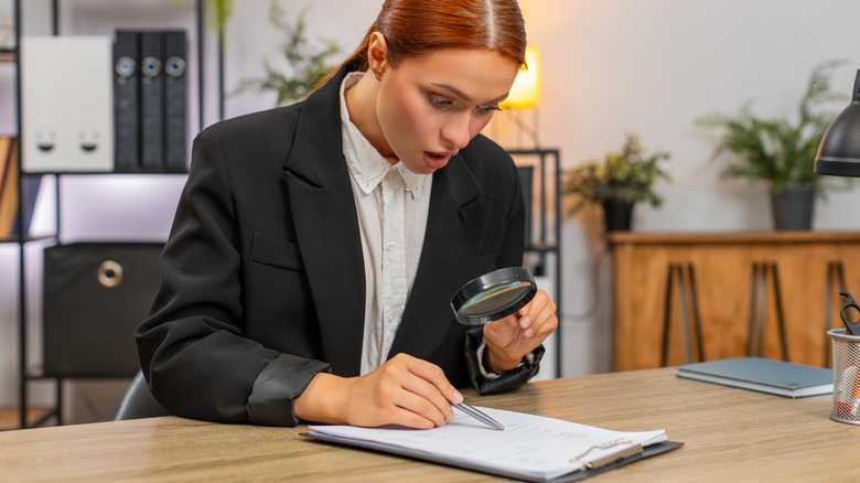 A trader surprised by the fine print on a contract with magnifying glass