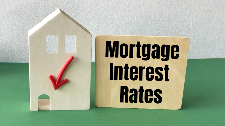 Piece of square wood and the word Mortgage interest rates and arrow to down and house.