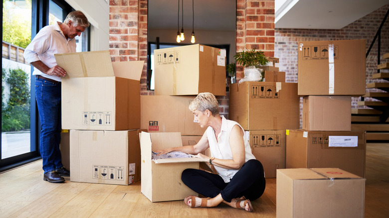 Senior couple surrounded by boxes unpacking in a new house.