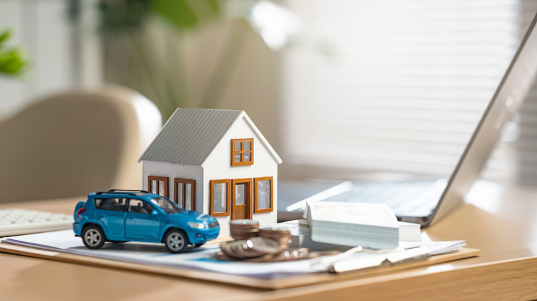 A blue car is on a table next to a house to represent home and auto insurance.