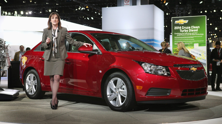 Chevrolet's Cristy Landi standing beside a red 2014 Chevrolet Cruz at an indoor conference