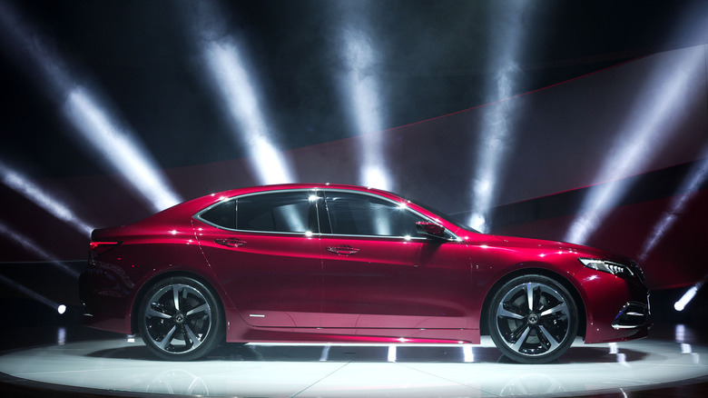 An Acura TLX on a raised dais at a car show with spotlights around it.