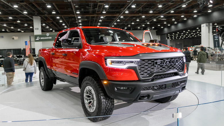 A red Dodge Ram 1500 truck on a raised dais at a car show.