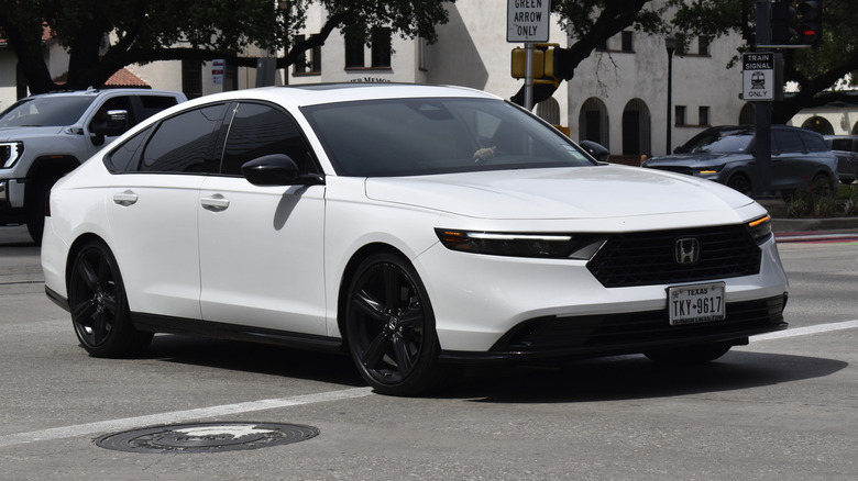 A portrait of a white Honda Accord sedan cruising in a downtown district near Hermann Park.