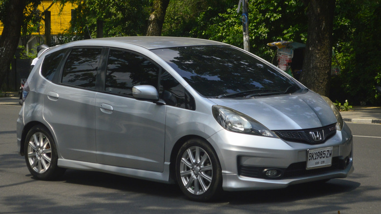 A gray Honda Fit driving on city street.