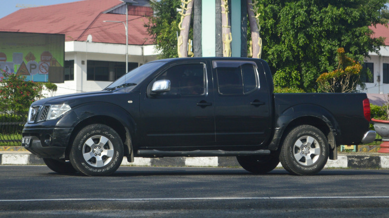 A black truck Nissan Navara Frontier 4WD driving on public road