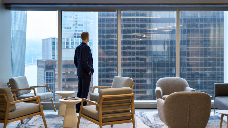 A titan of industry looking out the window with a view of the city.