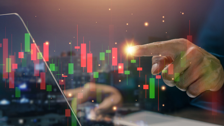 An investor tracking their assets with a candlestick chart graphic overlaid on top