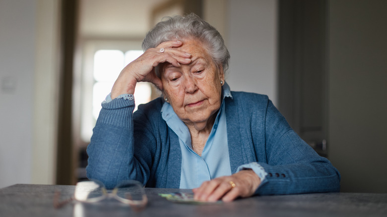 Unhappy senior woman counting her pension at home.