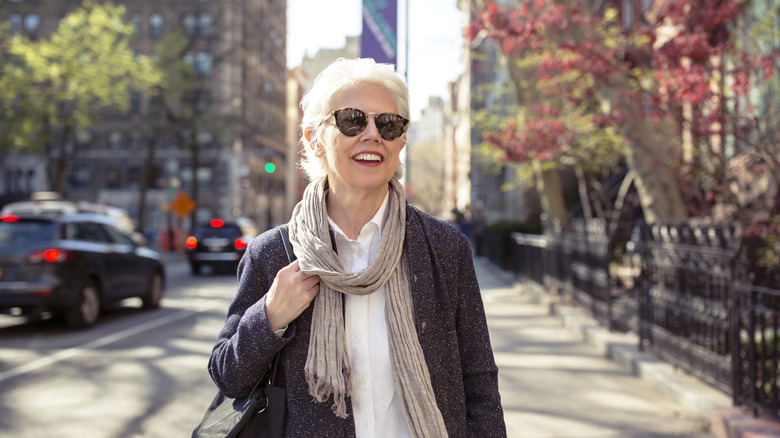 A fashionable mature women in shades walking down a street in New York City.
