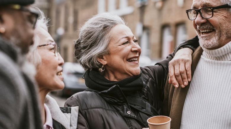 A group of happy seniors laughing together over coffee.