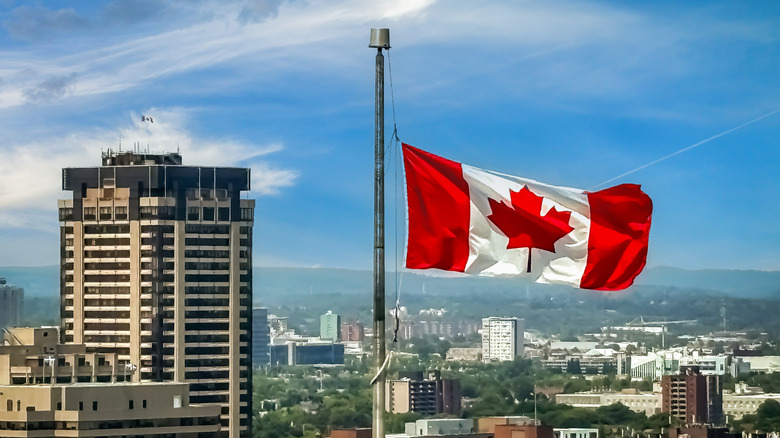 Canadian flag blowing in the wind at top of building