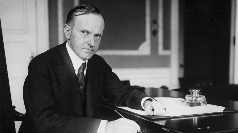 Calvin Coolidge (1872-1933), 30th President, sitting at his desk.