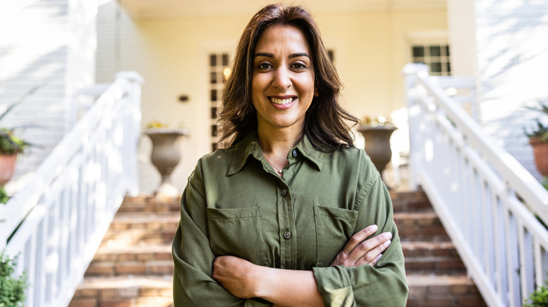 A smiling middle-aged woman standing in front of her front porch.