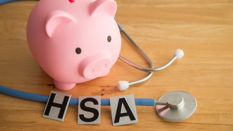 HSA alphabet, pink piggy bank and stethoscope on wooden table background.