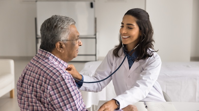 A cardiologist check heart rate of older male patient with stethoscope.
