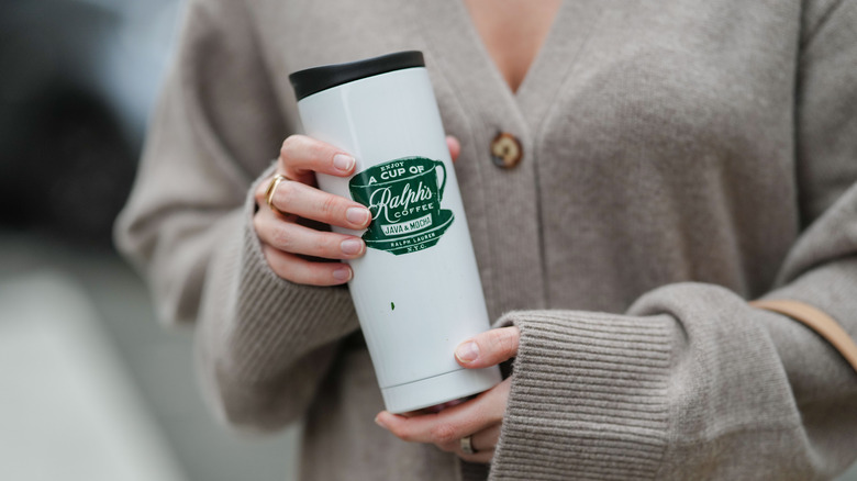 A close up of a woman holding a coffee mug.