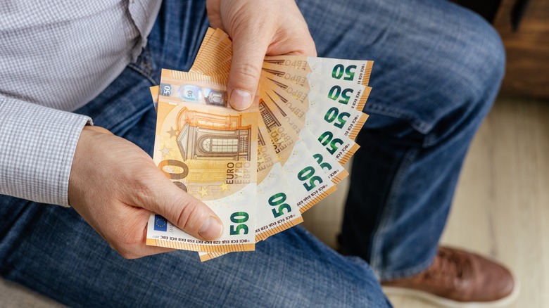 Businessman holding a fan of 50 euro banknotes in his hand.