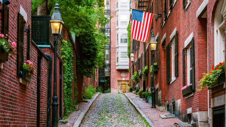 Red Brick houses along Acorn Street in Boston with an American flag flying in the foreground.
