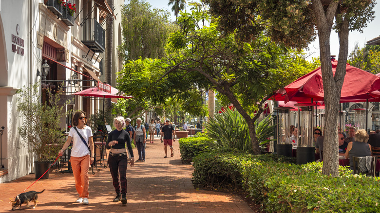 People walking along upscale shopping boutiques, cafes and patios offering local food and wine in Santa Barbara, California.