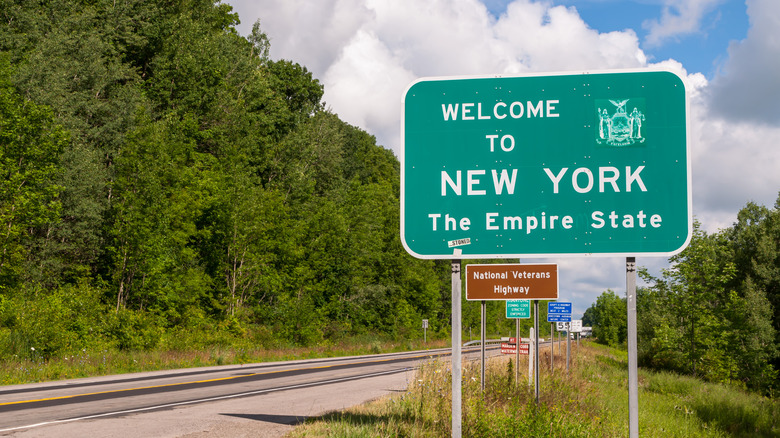 The Welcome to New York state line sign on U.S. Route 62 in Chautauqua County, New York, USA on a sunny summer day.