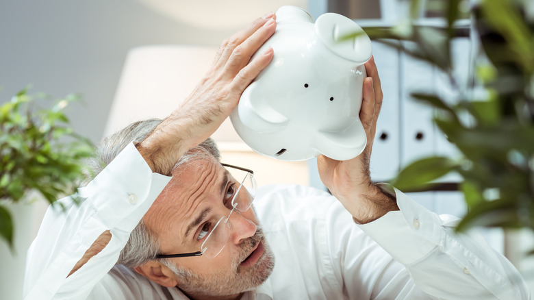 An elderly man holding a piggy bank