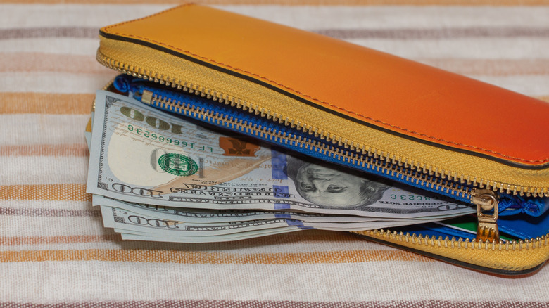 Wallet with $100 bills on a tablecloth