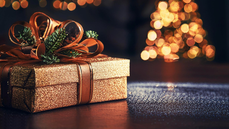 A gift box wrapped on a wooden table against the background of a beautiful Christmas tree