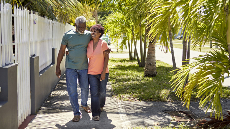 Retired couple walking along a street lined with palm trees