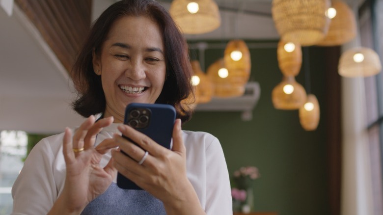 A woman smiling and looking at her smartphone