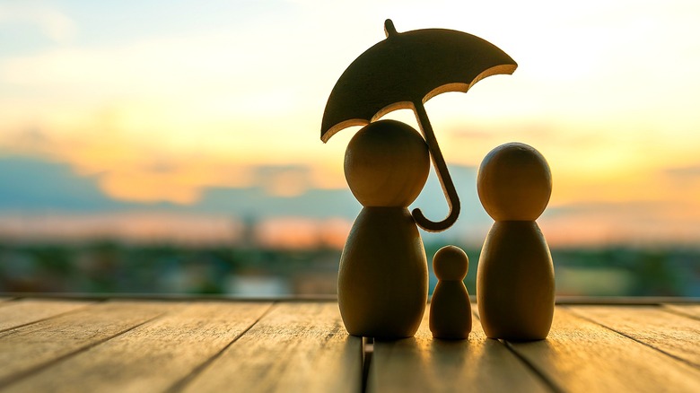 Wooden family figurines under umbrella