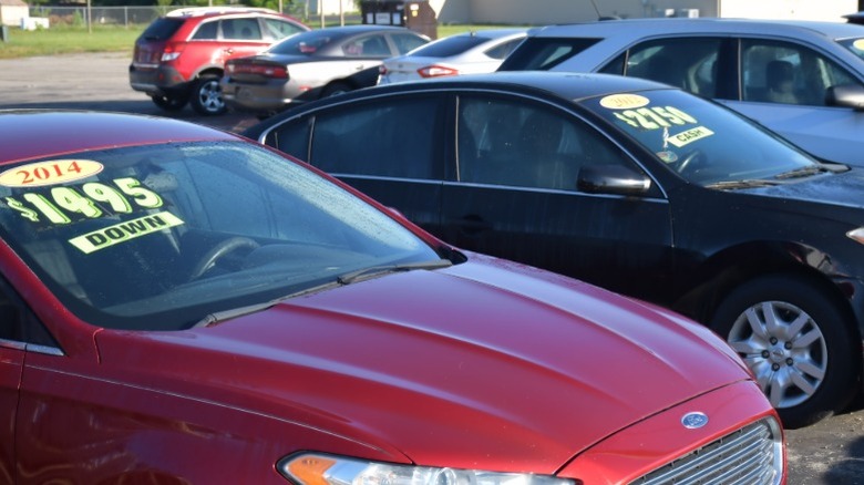 UJsed cars on a lot with stickers in their windshields advertising low starting down payment fees.