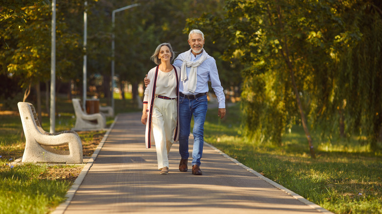 A retired couple walking outside in a park